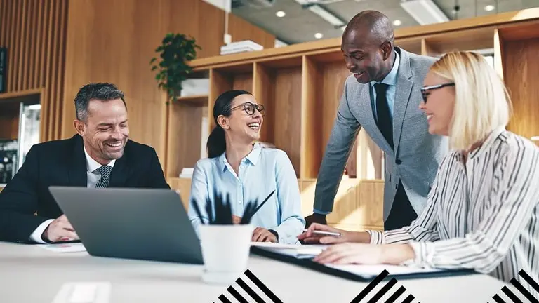 Group of people gathered round a laptop, likely looking at wellbeing documents. Make UK branded