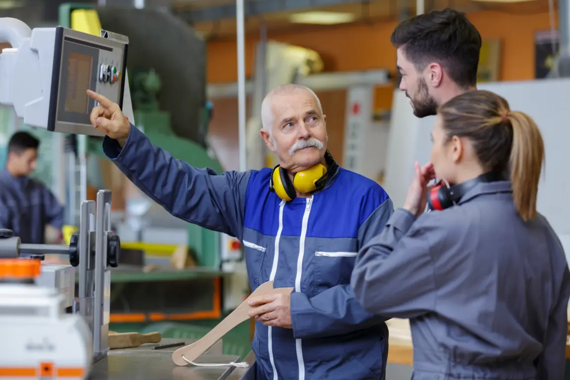 Experienced instructor shows younger employees how to operate machinery